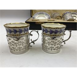 Boxed set of six Aynsley coffee cans and saucers, decorated with purple flowers in a black and yellow boarder, the cans within silver mounts, hallmarked Birmingham 1922