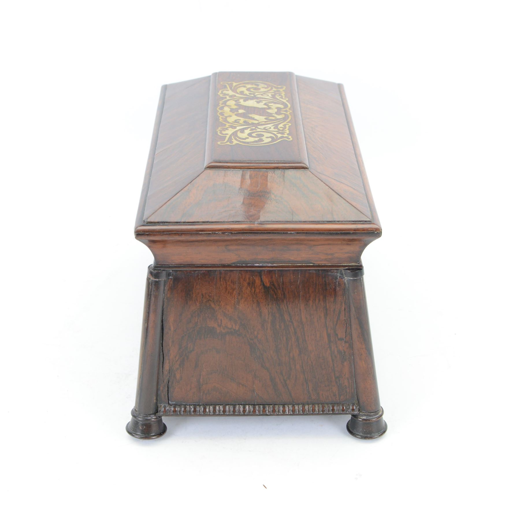 Early 19th century rosewood and brass inlaid tea caddy, of sarcophagus form, the front and hinged opening cover inlaid with brass scrolling panels, opening to reveal a compartmented interior with twin removable boxes with conforming inlaid brass detail to the hinged covers and zinc lining to the interiors, flanking a later glass mixing bowl, the whole upon four turned cylindrical feet, H21cm W36cm D20cm