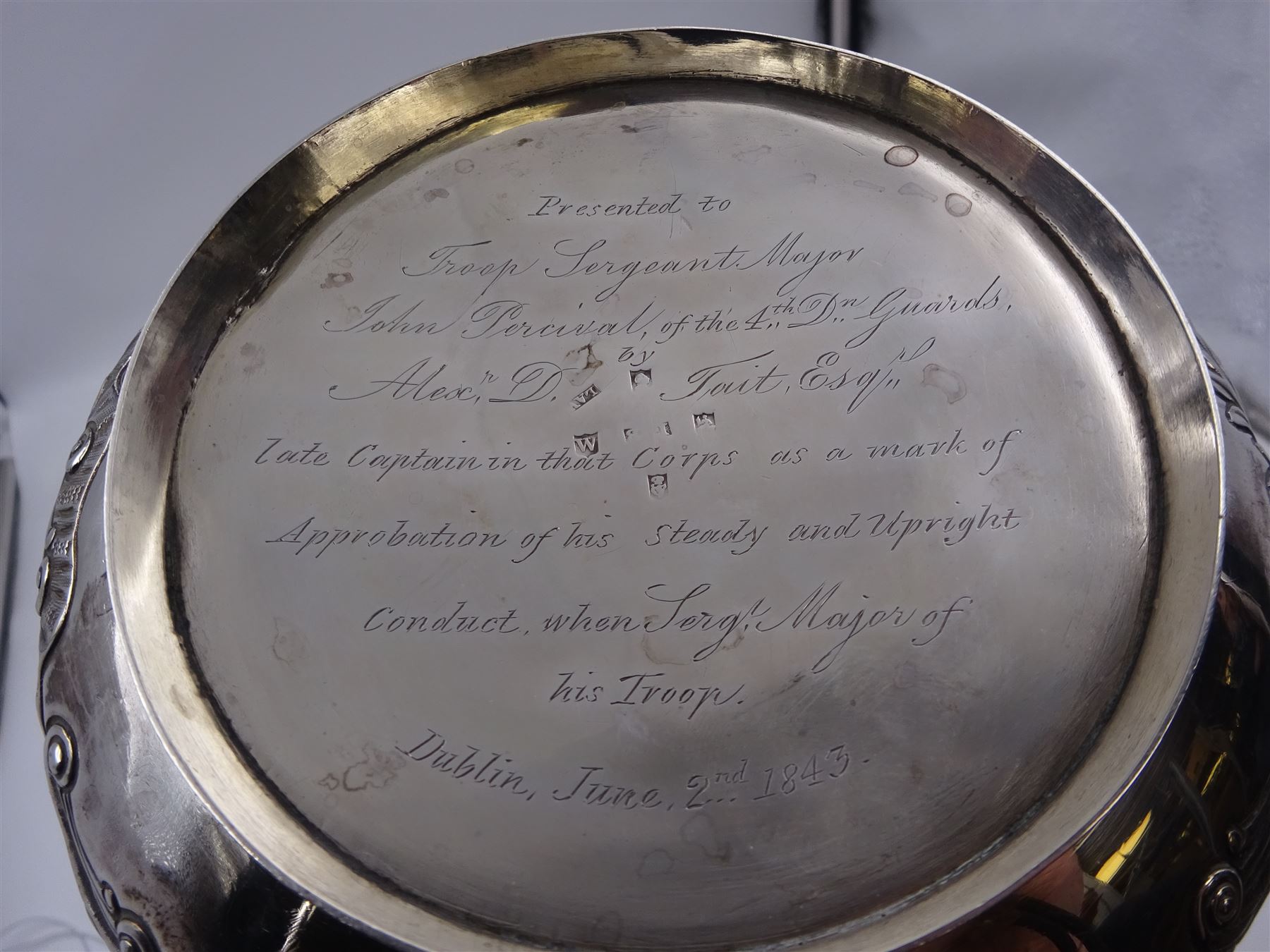 George III Irish silver teapot, of squat circular form, the body with repousse and chased floral and C scroll decoration, with capped C handle and ivory insulators, engraved to base 'Presented to Troop Sergeant Major John Percival, of the 4th Dragoon Guards by Alex D. Tait, Esq, late Captain in that corps as a mark of approbation of his steady and upright conduct when Sergeant Major of his Troop, Dublin, June 2nd 1843', hallmarked William Law, Dublin 1817, H12.5cm, This item has been registered for sale under Section 10 of the APHA Ivory Act