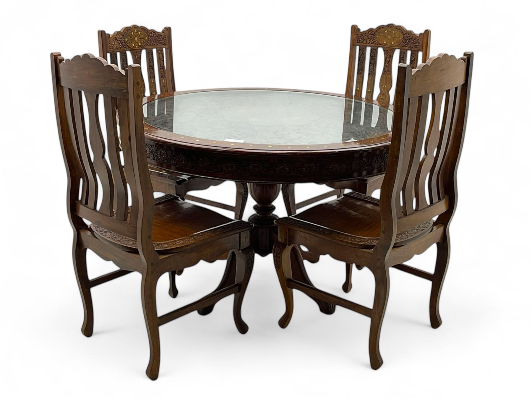 Pakistan carved hardwood brass inlaid circular dining table, and four rail back chairs with saddle seats