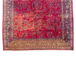 Large Persian-style mahal-type hand-knotted carpet, of rectangular form with a deep crimson field decorated with an all-over arrangement of stylized floral sprays and palmettes, with a central subtle medallion composition enclosed by a dark navy main border of scrolling floral motifs between narrow guard stripes with fringe ends 
