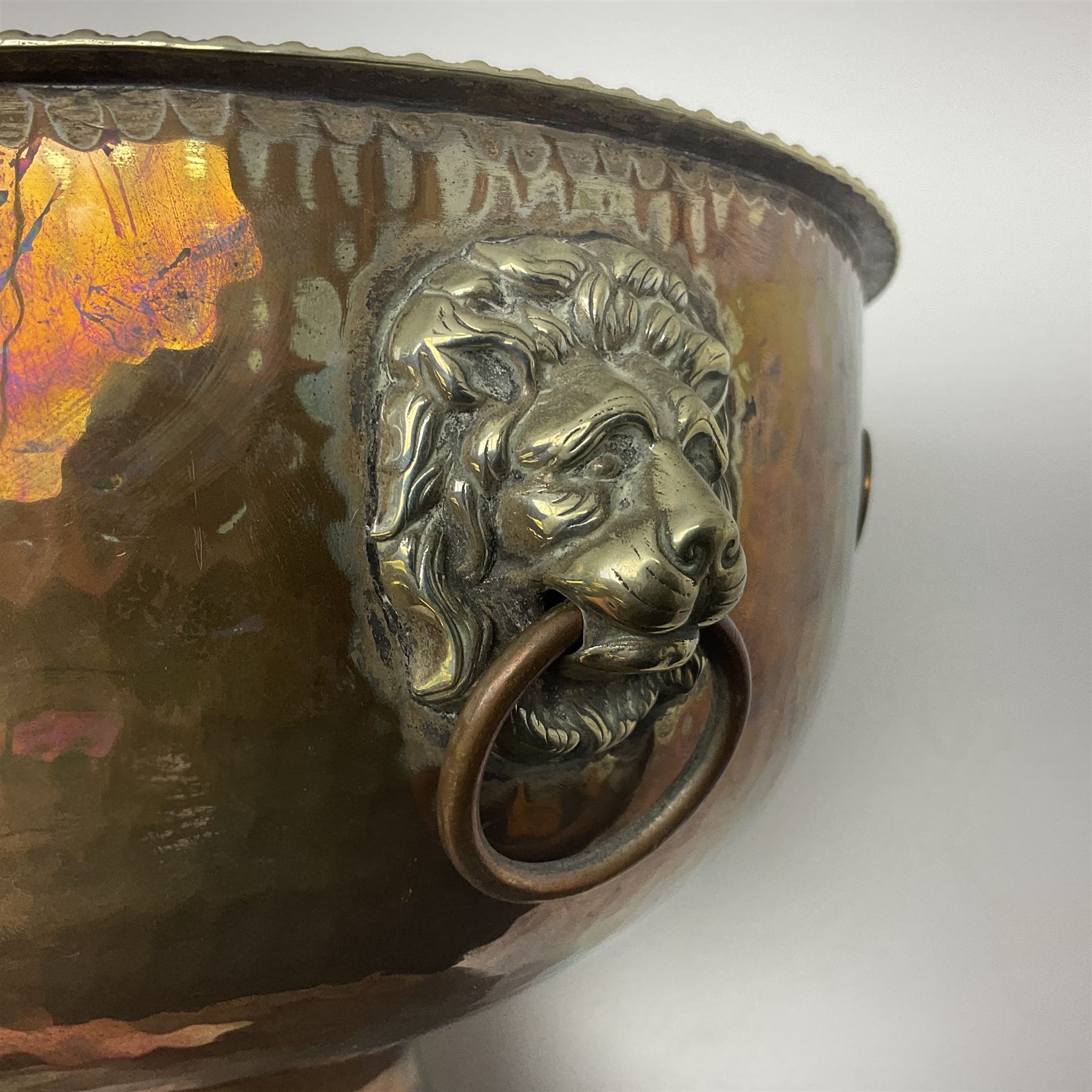 Copper pedestal punch bowl, with planished decoration with twin lion mask and ring handles and applied coins, H18cm