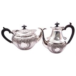 Early 20th century silver teapot and matching coffee pot, each of oval form with ebonised handles and finials, repoussé decorated with vacant shaped panels, C scrolls, part fluting, flower heads and foliate scrolls, hallmarked Thomas Edward Atkins, Birmingham 1913, approximate total gross weight 31.79 ozt (988.7 grams)