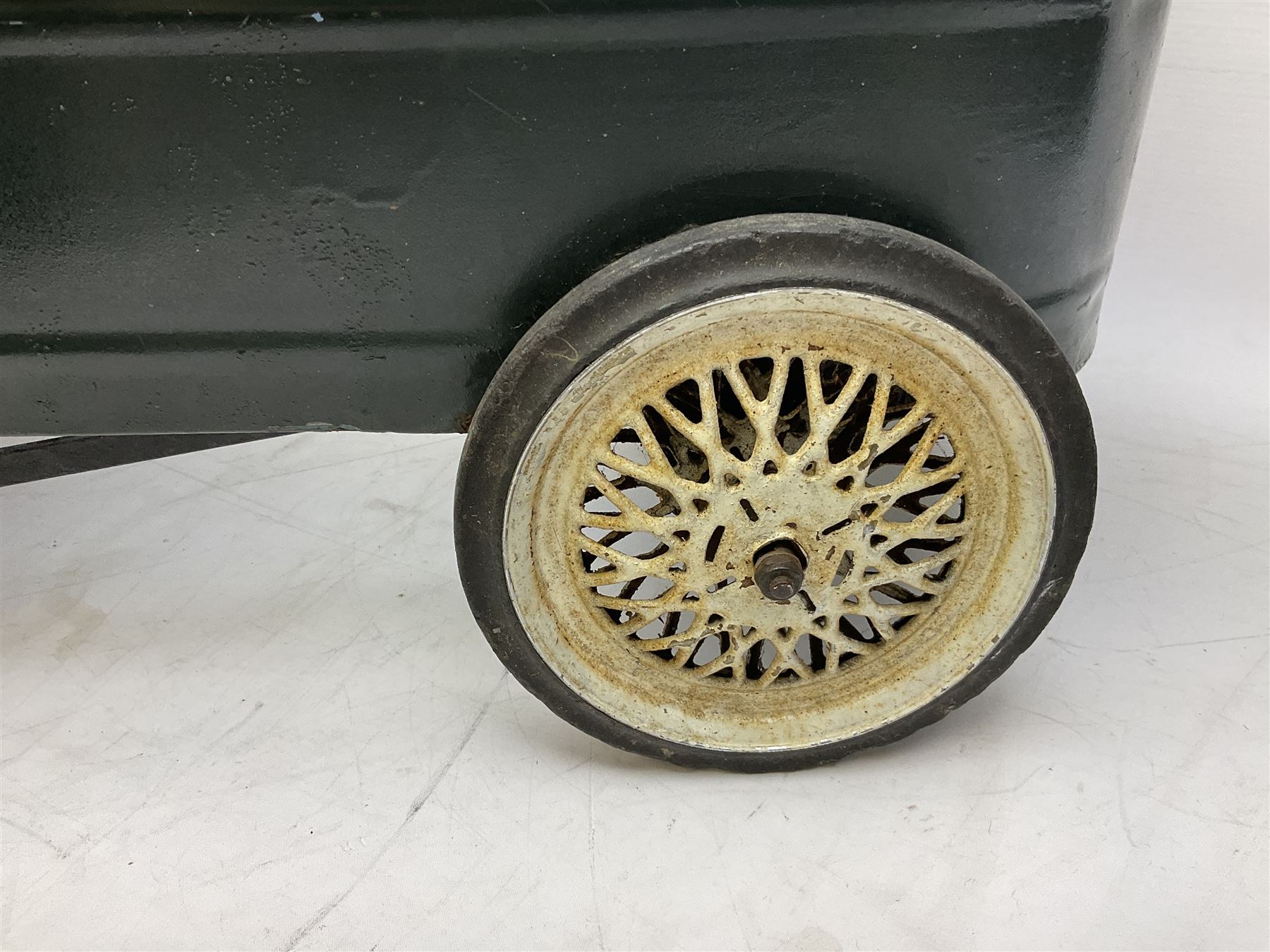 Mid 20th century pressed steel pedal car, the body painted in dark green fitted with pretend radiator to the bonnet, with spoked wheels and rubber tyres, the interior with pedals and steering wheel, L70cm