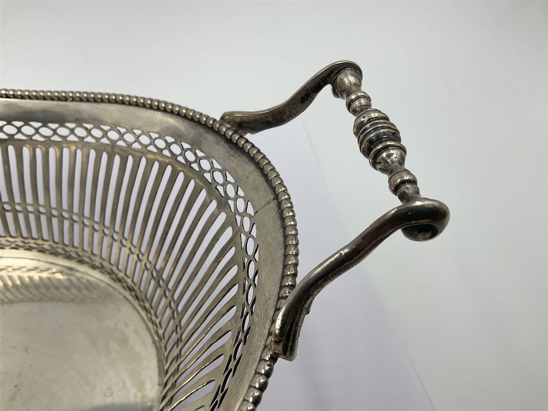 Early 20th century Dutch silver basket, of oval form with pierced sides, beaded rim, and twin handles, marked with Lion Passant for 2nd standard purity and date letter for 1910, other marks worn and indistinct, including handles H8.5cm L25.5cm