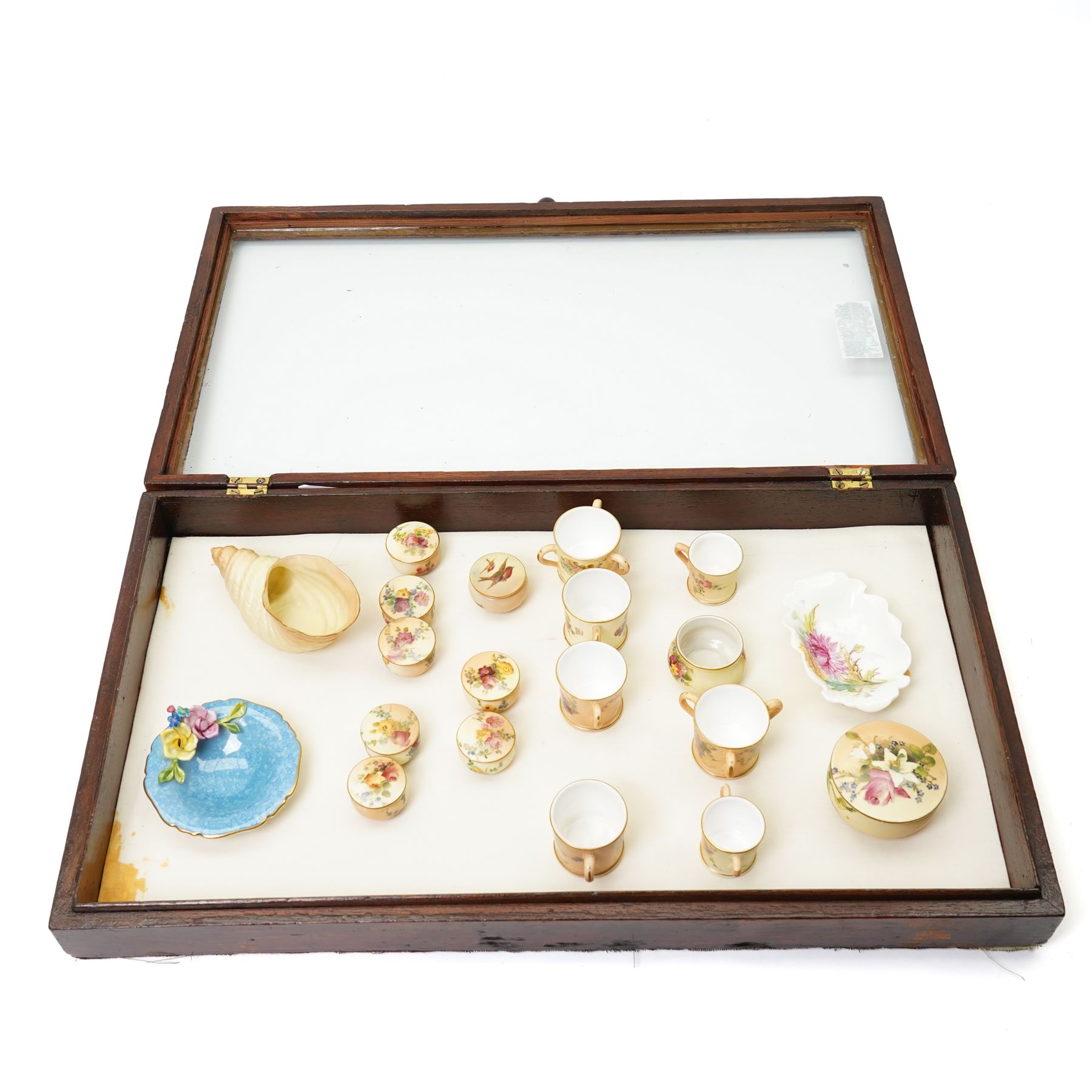 Large collection of miniature Royal Worcester hand-painted blush ivory wares, including shell shaped dish, and various covered trinket dishes, in glazed display case