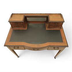 Maple & Co - Edwardian mahogany inlaid writing desk, the superstructure with pierced brass gallery, above an inset mirror and two short drawers, inset leather writing surface, bow fronted with crossbanded drawers and brass swan neck handles, square tapering supports terminating in castors 
