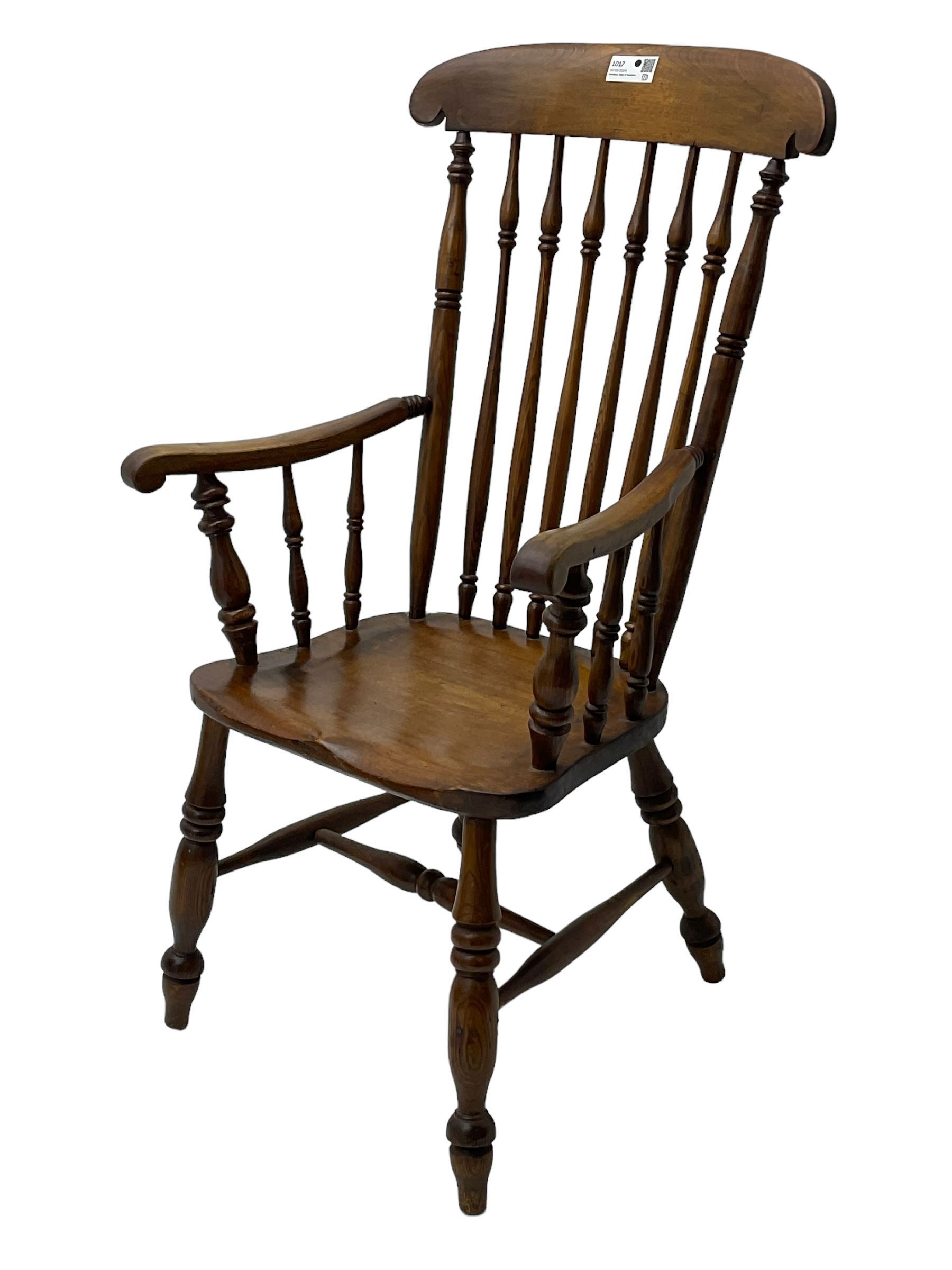 Early 19th century elm farmhouse armchair, the shaped eared cresting rail over tall spindle back, dished seat on turned supports united by H stretchers