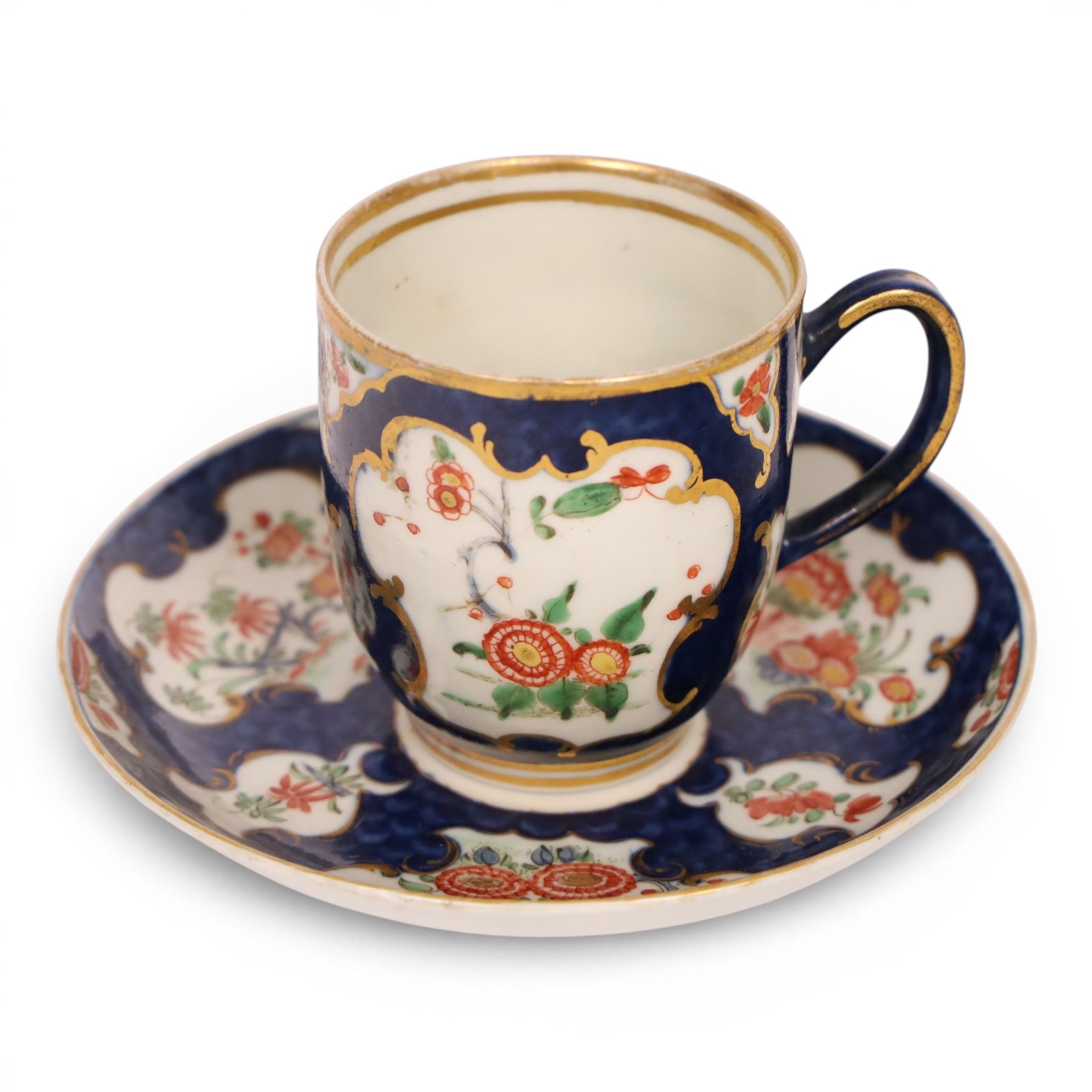 18th century Worcester coffee cup and saucer, circa 1770,  painted with shaped panels of chrysanthemums and banded hedges on a blue scale ground with gilt detail to the rim, mark beneath, H8cm 