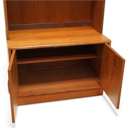 G-Plan - ‘Fresco’ teak bookcase cabinet, rectangular open bookcase with mirrored back panel to the upper section, fitted with a single glass display shelf and two wooden shelves below, the base enclosed by a pair of cupboard doors with shaped teak handles, on a plinth base