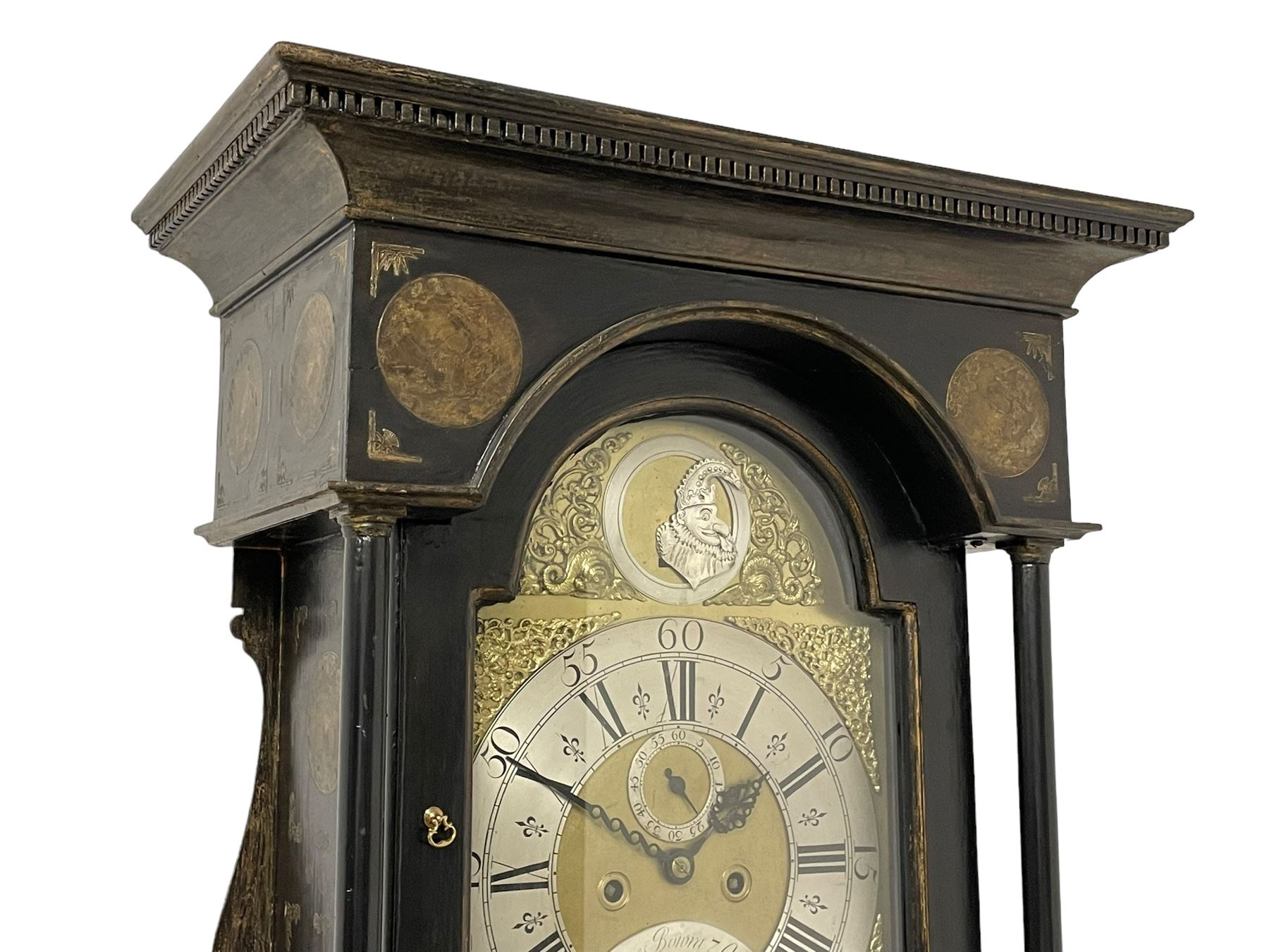 James Bowra of Sevenoaks Kent - 18th century 8-day ebonised longcase clock with gilt decoration c1740, with a flat top, dentil moulding beneath and shaped back splats, break arch hood door flanked by plain pilasters with wooden capitals, long trunk with a curved topped door, on a square plinth with canted corners and raised on a moulded base, brass dial with cast spandrels and a silvered 'Punch' automata to the arch, matted dial centre with seconds ring and date aperture, silvered chapter ring with Roman numerals, five minute Arabics, minute and quarter hour tracks, with matching steel hands and silvered makers name plate, rack striking movement with a recoil anchor escapement, striking the hours on a bell. With weights and pendulum.
