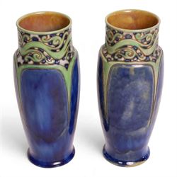 Royal Doulton - Pair of Art Nouveau vases, designed by Francis Pope, with scroll work to the collar, in tones of green and blue, with impressed mark and no. 8138 beneath, H26cm