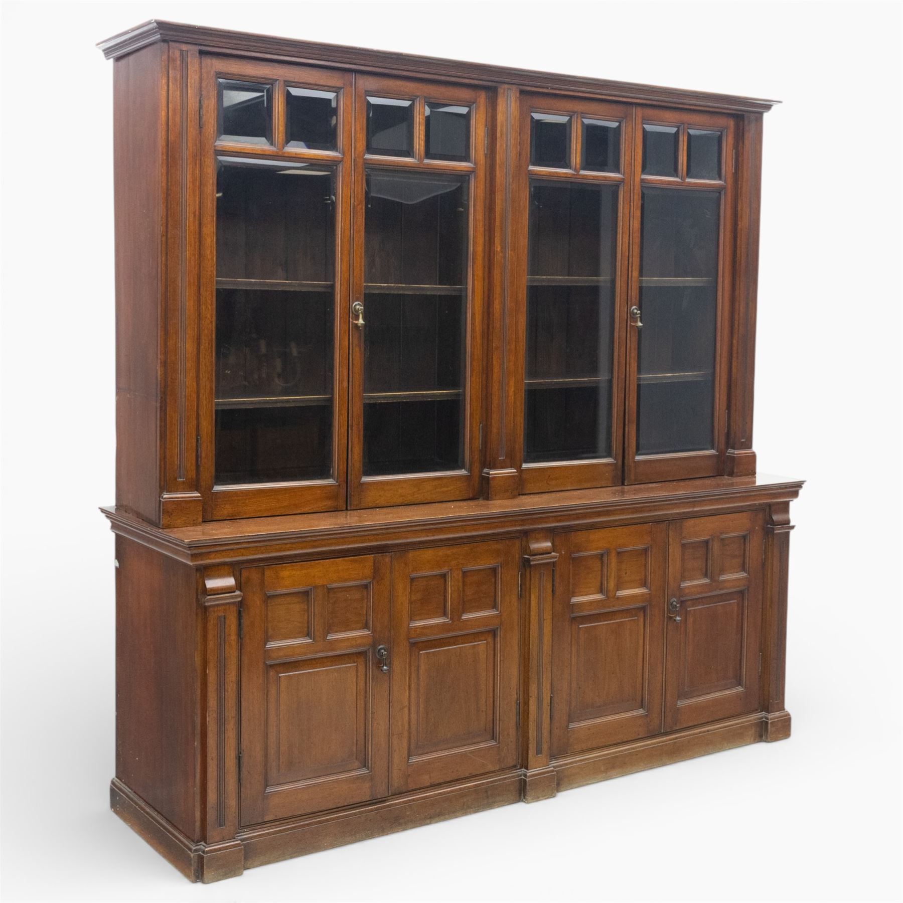Late 19th century walnut library bookcase, fitted with four display doors with astragal bevelled panes, raised upon a four cupboard base with fielded panel doors
