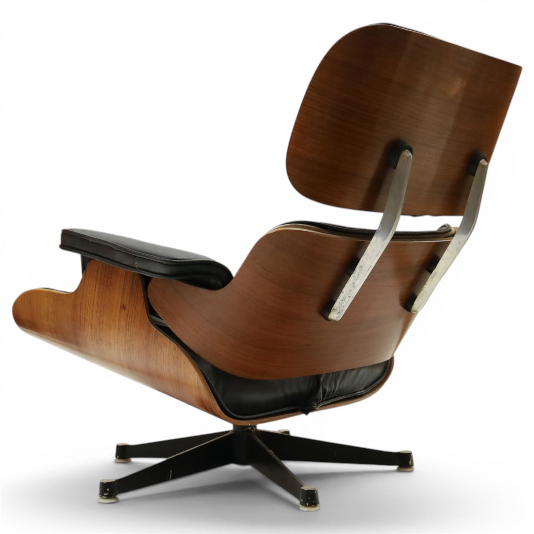 Charles and Ray Eames for Herman Miller - lounge chair, moulded veneered plywood shell with buttoned black leather upholstery, separate headrest and back cushions, padded armrests, on black cast aluminium five-star swivel base, manufactured under licence by Hille of London