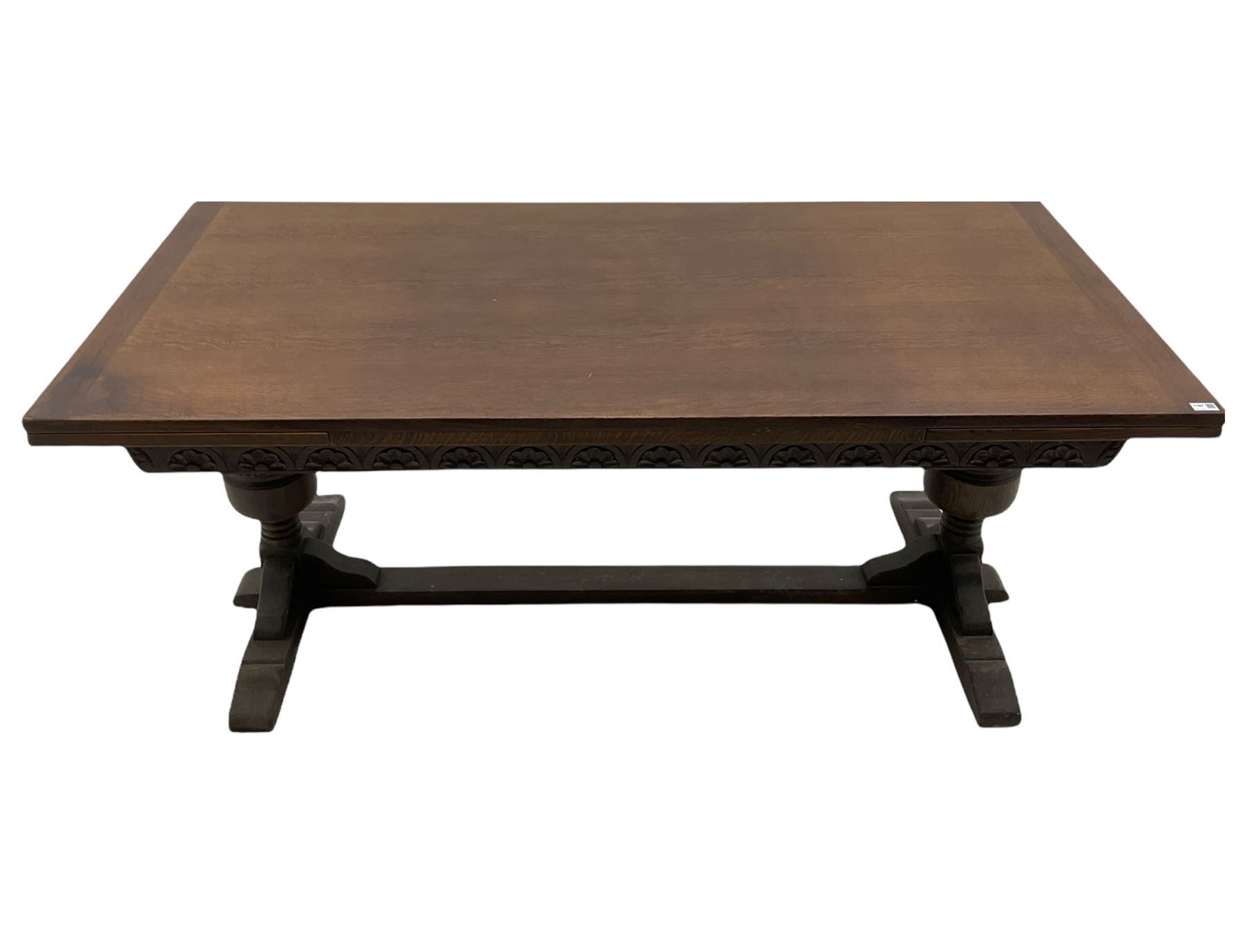 20th century oak drawer leaf extending dining table, two foliage carved baluster supports on sledge feet joined by floor stretcher 