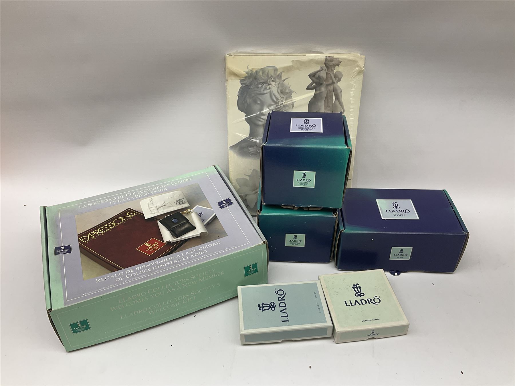 Lladro Collectors Society items, comprising of The Will to Create book, two candle holders; Sailing the Sea no 17665, Dolphins at Play no 17666, Plaque Bringing Us Together, key fob, leather wallet and a members joining pack with plaque, all in original boxes  