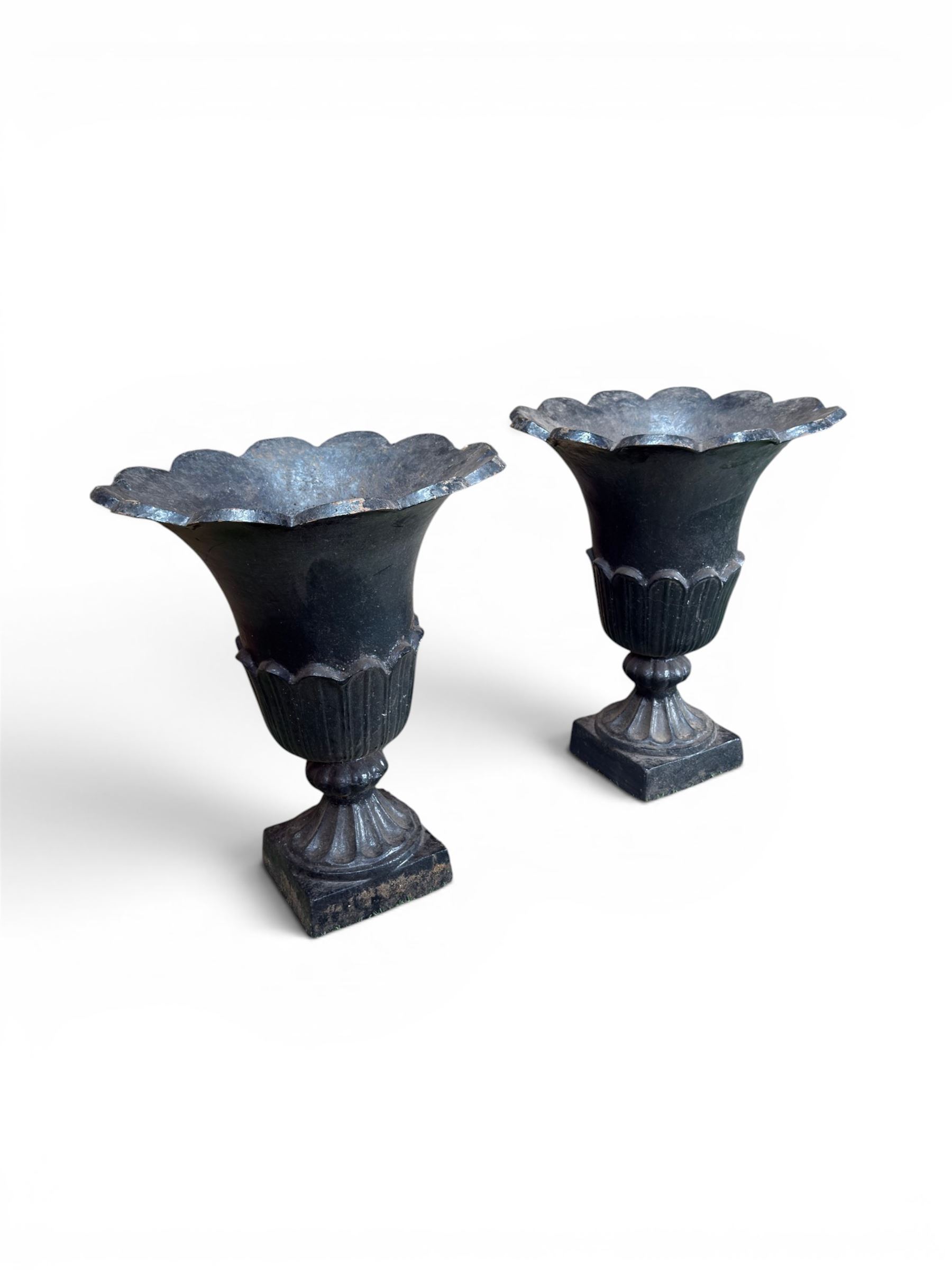 Pair of Victorian large scale cast iron garden urns, flared petal shaped rim with tapering waist, gadrooned base on square plinth, finished in black paint