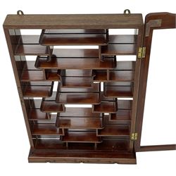 Chinese hardwood wall hanging curio cabinet, the mirror interior fitted with stepped shelves, enclosed by single glazed doors, decorated with carved scrolling foliage 