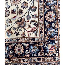 North East Persian Meshed hand-knotted rug, ivory field with scrolling vines, palmettes, and rosettes in shades of blue and brown, within a dark blue border of palmettes and flowerheads between multiple guard stripes, with cotton fringe ends  