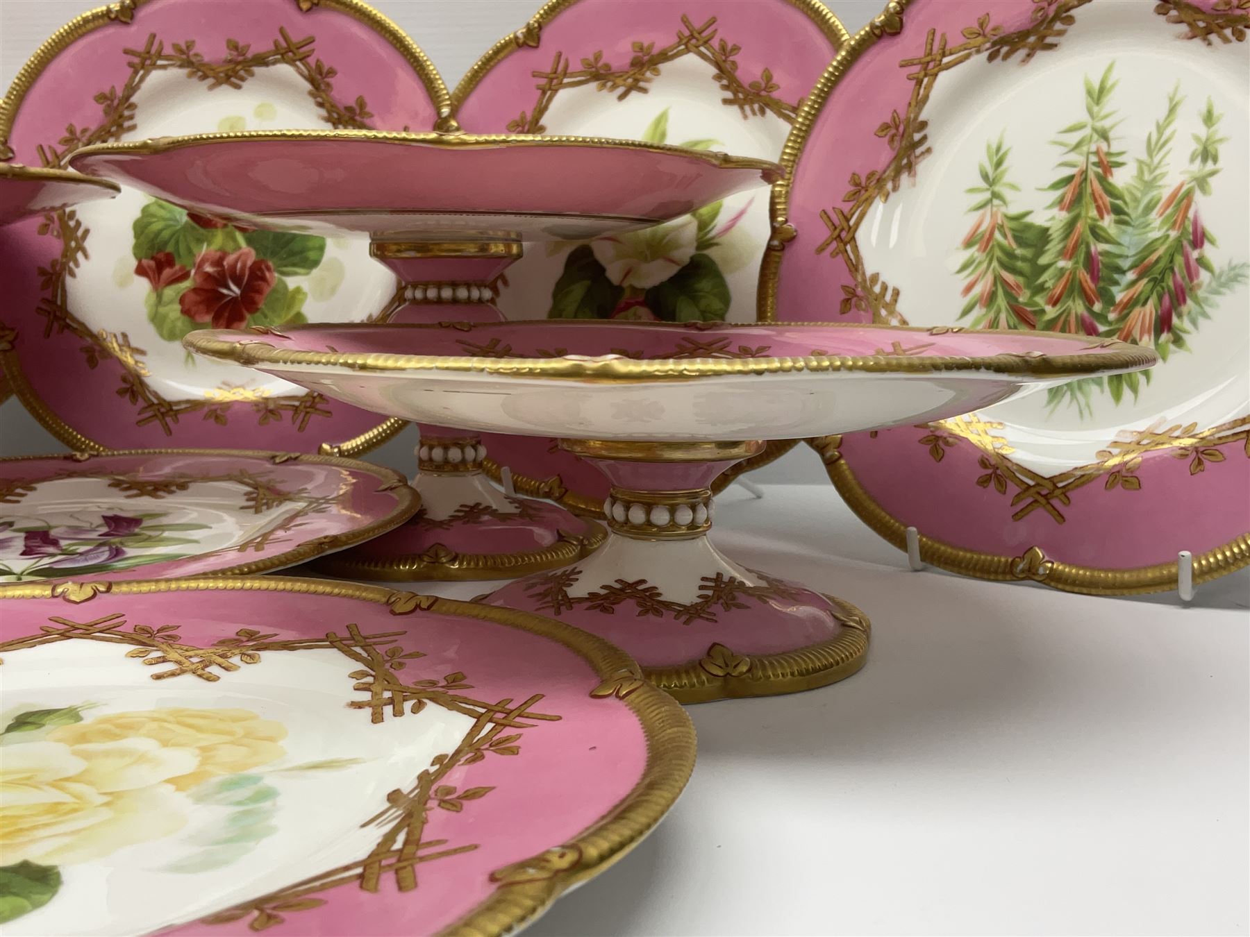 Victorian dessert service, comprising four comports and nine plates, each decorated with floral sprigs to the centre with a pink and gilt border, largest comport H13cm, plate D22.5cm