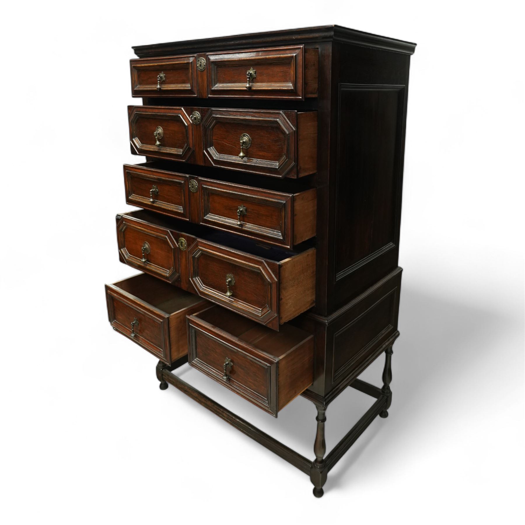Jacobean style oak chest on stand, four full-length graduated drawers decorated with geometric mouldings, brass pear drop handles and escutcheon, the stand with two drawers above turned legs on a stretcher base on all sides, raised on pear-shaped feet, 18th century and later 

 