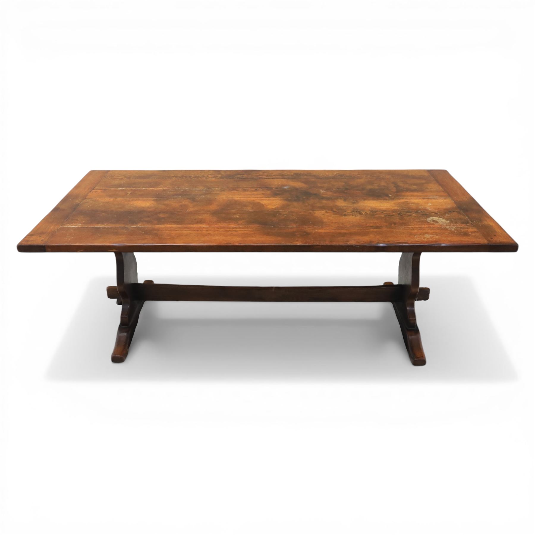 Carolean revival oak dining table and eight chairs (7+1), refectory table with rectangular boarded top and cleated ends, raised on shaped trestle end supports with central stretcher, accompanied by eight high-back chairs including a carver, leather upholstered panels and seats with studwork, on turned legs with stretchers.