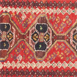 Northwestern Persian village rug, madder red field, with serrated central panel enclosing three linked lozenge medallions, polychromed spandrels, ivory border, and geometric guard stripes  