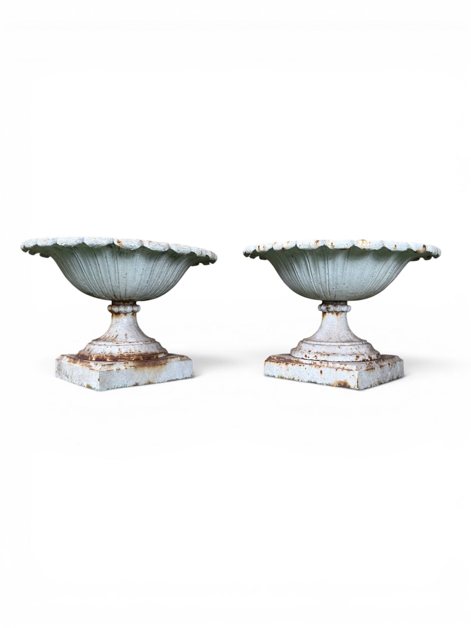 Coalbrookdale - pair of 19th century cast iron petal rim urns, squat form on square plinth, finished in distressed white paint, design registration number 133334, first registered 19 september 1860, number 19 in the Coalbrookdale Castings Catalogue (see illustration)