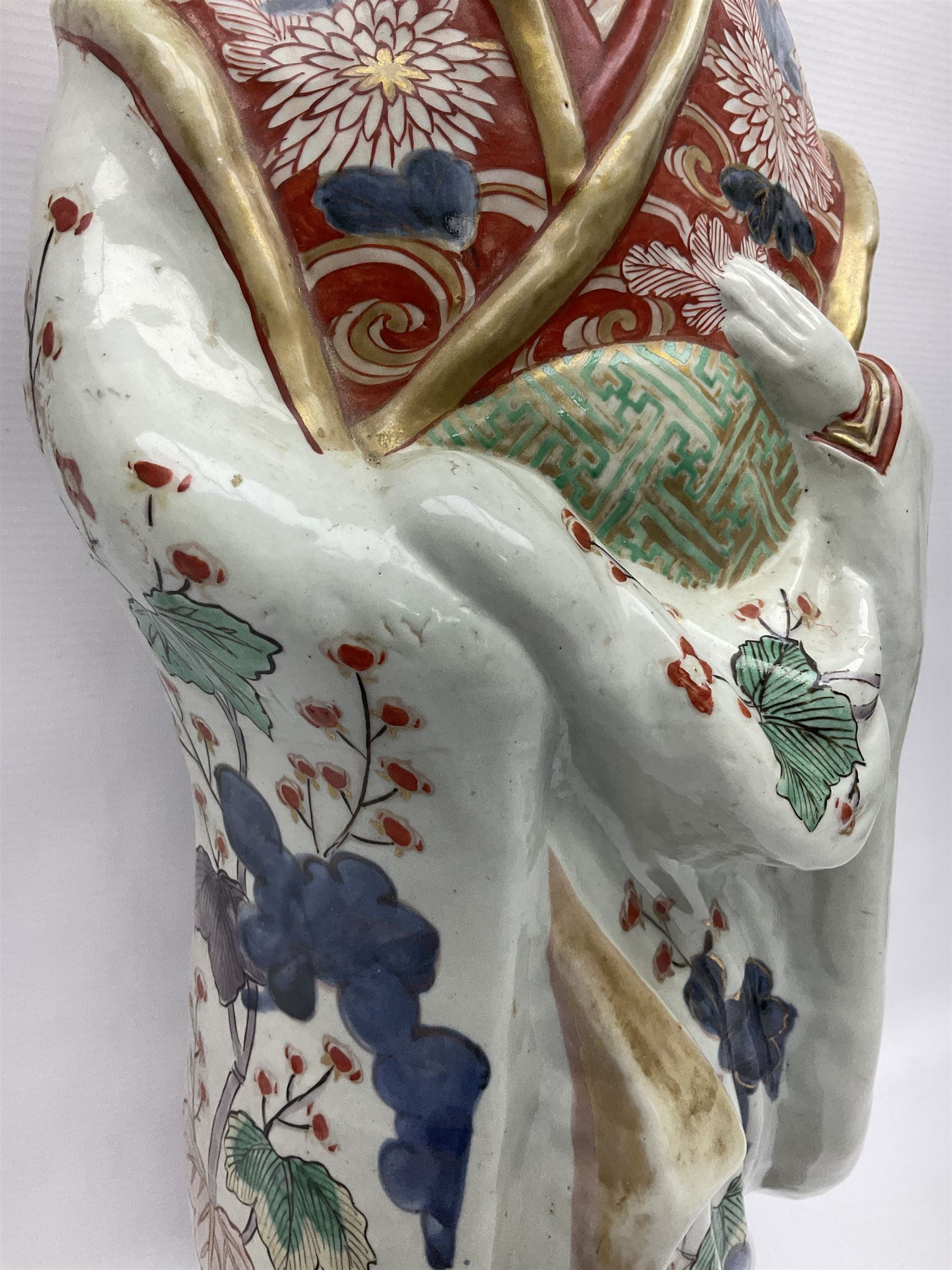 Large Japanese Imari porcelain figure, modelled as a Bijin, wearing a long kimono decorated with apple blossom and leafy branches on a white ground, with gilt detailing, possibly Edo period, H63cm