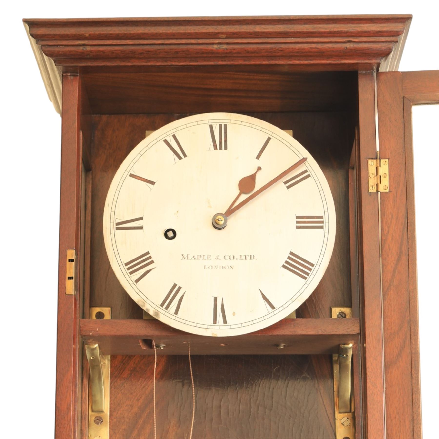 Edwardian mahogany regulator longcase clock, retailed by Maple & Co. Ltd., London, moulded cornice over glazed case enclosing a circular painted Roman numeral dial, single train weight-driven movement with brass cased weight and pendulum, on plinth base