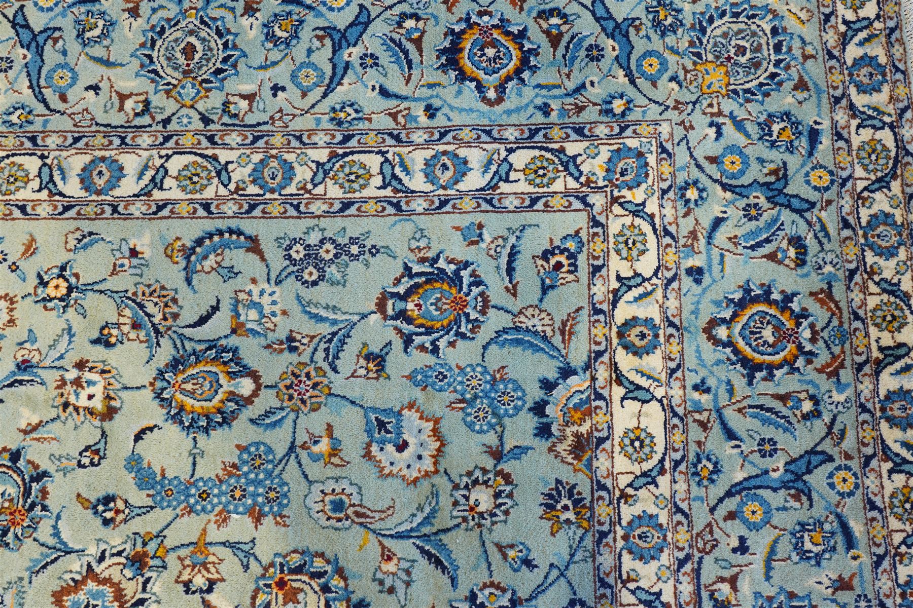 Central Persian Kashan hand-knotted carpet, pale blue field decorated with an all-over scrolling floral vine design incorporating stylized palmettes, rosettes and foliate sprays enclosed by a conforming floral vine border between multiple guard stripes, with cotton fringe ends 