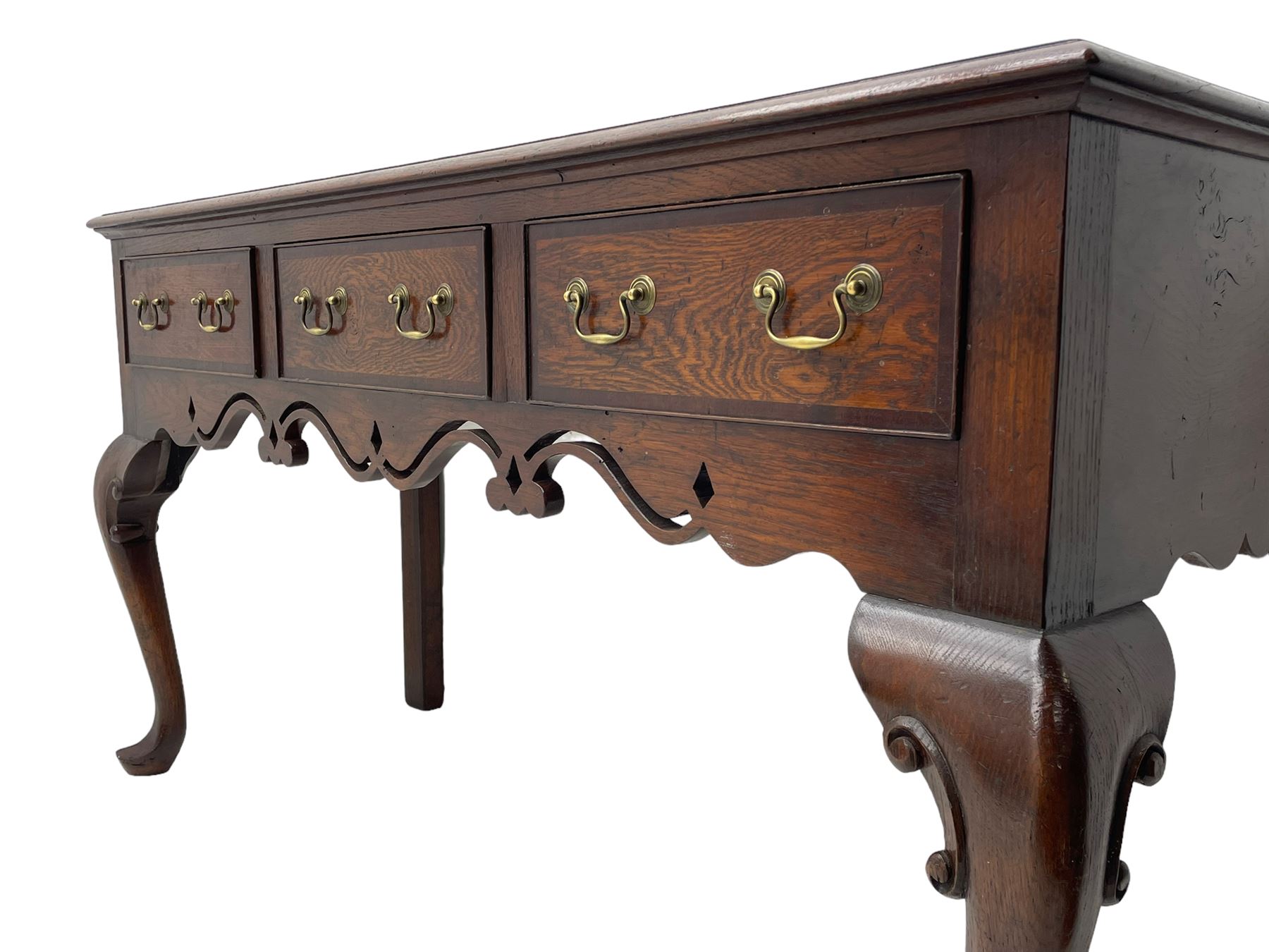 Georgian design oak and mahogany dresser base, the rectangular moulded top with mahogany band, three cocked-beaded and banded drawers over shaped a pierced apron, circular brass handle plates and swan neck handles, on C-scroll carved cabriole supports 