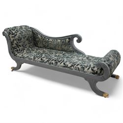 Regency design hardwood-framed chaise longue, scrolled back upholstered in leafy branch pattern fabric, reeded and scroll carved frame, on out splayed feet with brass paw castors