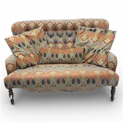 Late 20th century Liberty upholstered two seater sofa, the shaped back and arms with deep buttoned upholstery, covered in Art Nouveau fabric with stylised floral and foliate motifs, loose scatter cushions en suite, raised upon turned tapering front supports and swept rear legs