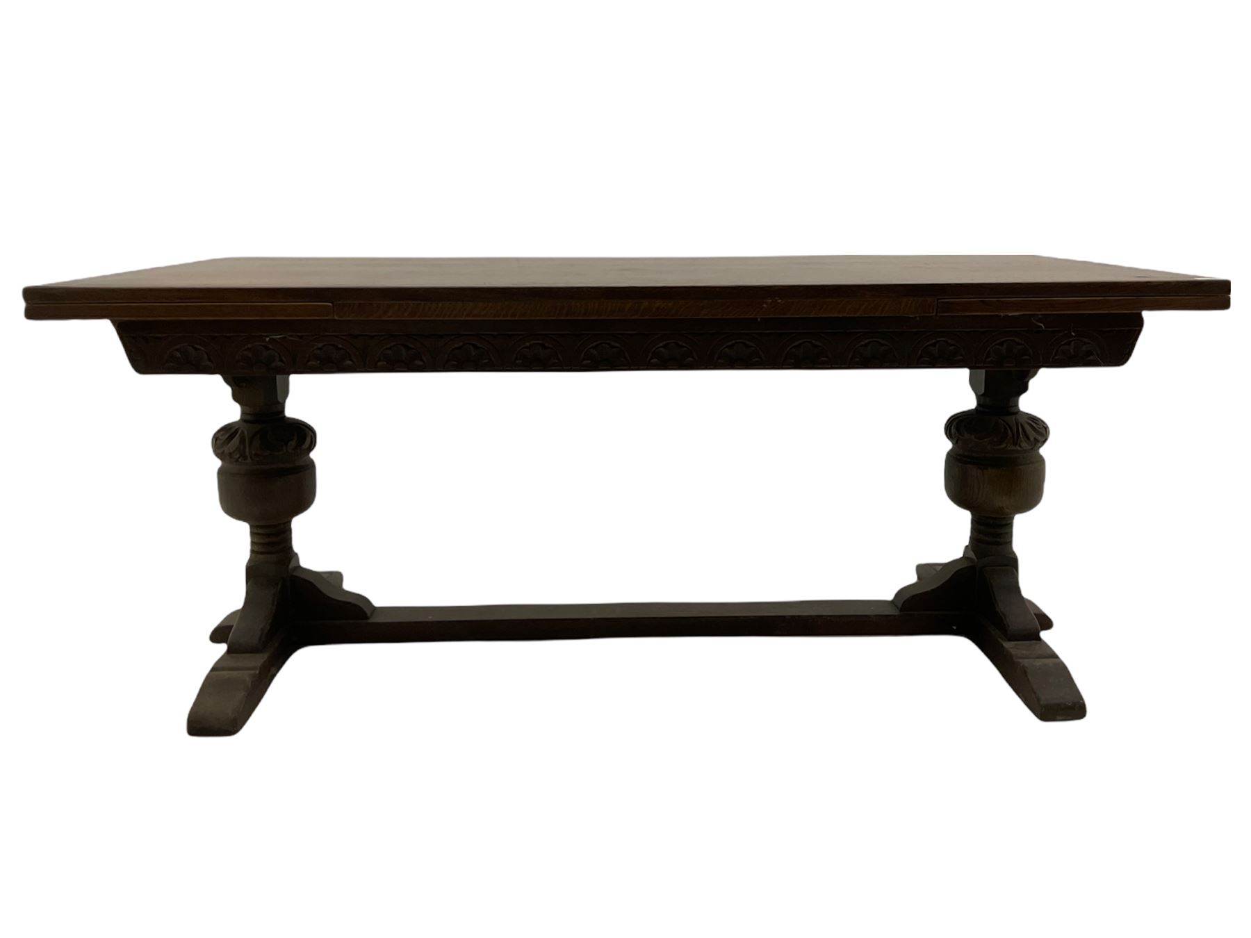 20th century oak drawer leaf extending dining table, two foliage carved baluster supports on sledge feet joined by floor stretcher 