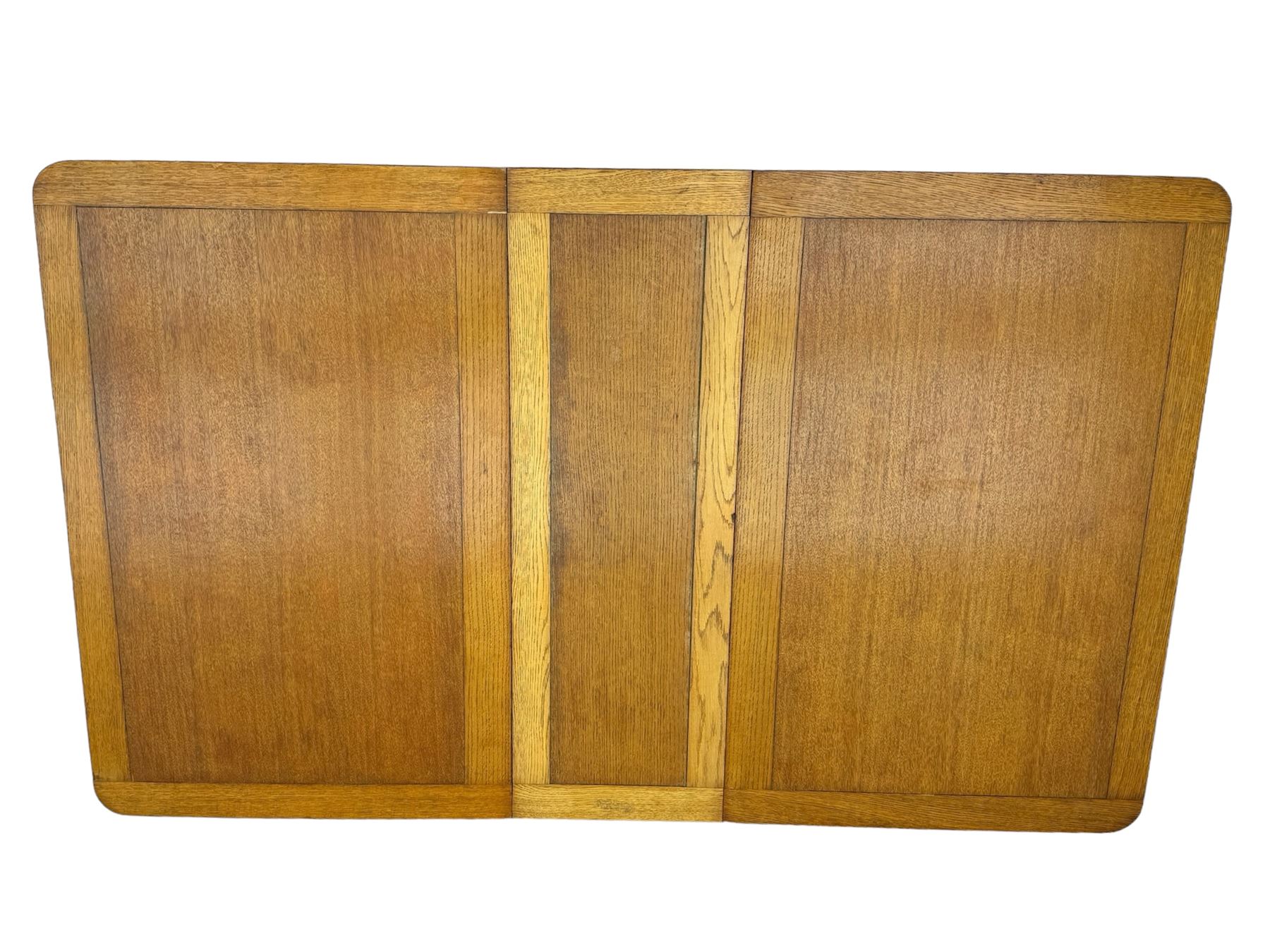 Early 20th century oak drop-leaf table, in the style of Harris Lebus, featuring rectangular top over central pedestal base, with two drawers and two cupboards, on gateleg supports