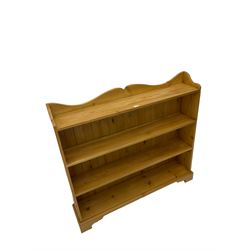 Waxed pine bookcase, shaped pediment over four tiers, on bracket feet