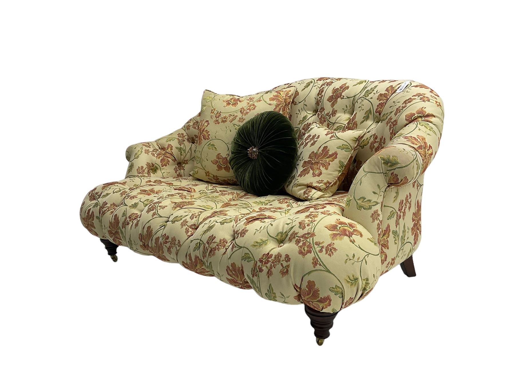 Victorian style two seat sofa, upholstered in beige ground floral floral pattern fabric, with scatter cushions, turned feet with brass castors