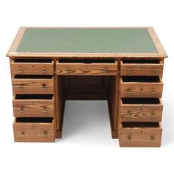 Contemporary stripped and waxed pine pedestal kneehole desk, rectangular top inset with green leather writing surface with brass studded edge, fitted with nine drawers with brass knob handles, above a plinth base on recessed castors