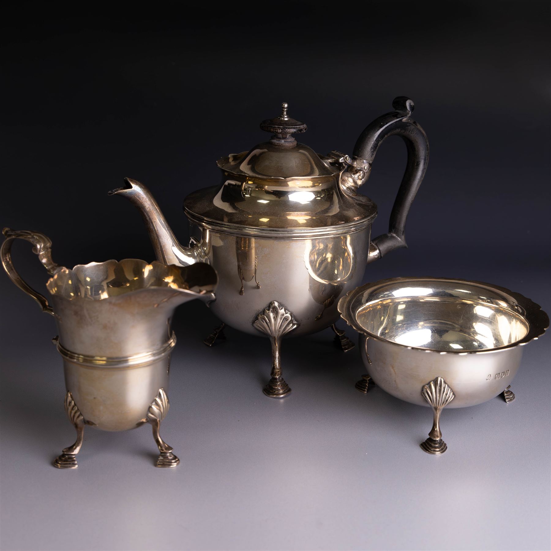 Early 20th century silver three piece bachelor's tea service, comprising teapot, open sucrier and milk jug, all of circular waisted form with shaped rims and upon three stepped feet, the teapot with ebonised wooden handle and finial, hallmarked Wakely & Wheeler, London 1914, teapot height H15cm