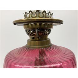Victorian table standing oil lamp, brass fittings, cranberry glass reservoir, brass column on black enamelled ceramic base, with a frosted glass shade and clear glass chimney, H68cm