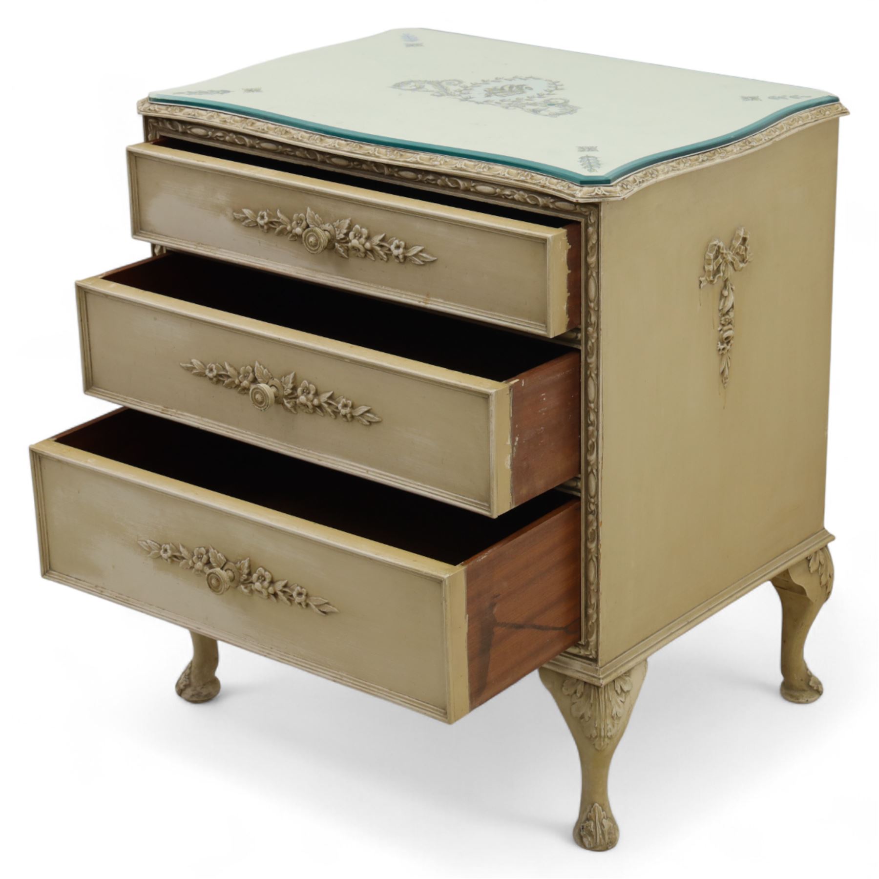 French design cream painted three drawer commode, shaped front with floral garland appliqués, fluted uprights and acanthus carved cabriole legs terminating in scroll feet