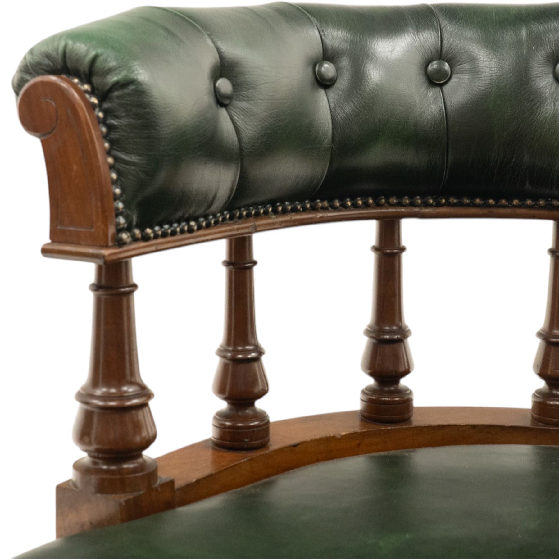 Late Victorian mahogany framed Captains tub desk chair, the green leather upholstered cresting rail over turned spindle supports over a sprung seat, raised on front turned supports terminating to ceramic castors