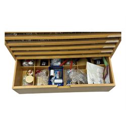 Large beech haberdashery thread storage cabinet, rectangular form with fourteen glass-fronted sloping drawers housing an extensive array of thread spools in assorted colours, over two larger drawers, raised on plinth base