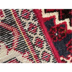 Persian Joshaghan crimson ground rug, stepped lozenge medallion surrounded by repeating foliate lozenge motifs, the border decorated with stylised plant motifs, within geometric guard stripes 