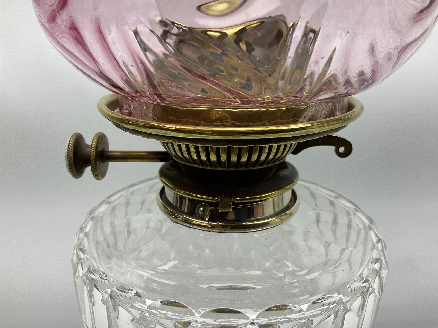 20th century Hawksworth, Eyre & Co silver plated oil lamp, the octagonal stepped base with engraved dedication, leading to an octagonal column supporting a faceted clear glass reservoir, Hinks Duplex burner, clear glass chimney, and cranberry glass shade, overall H71.5cm