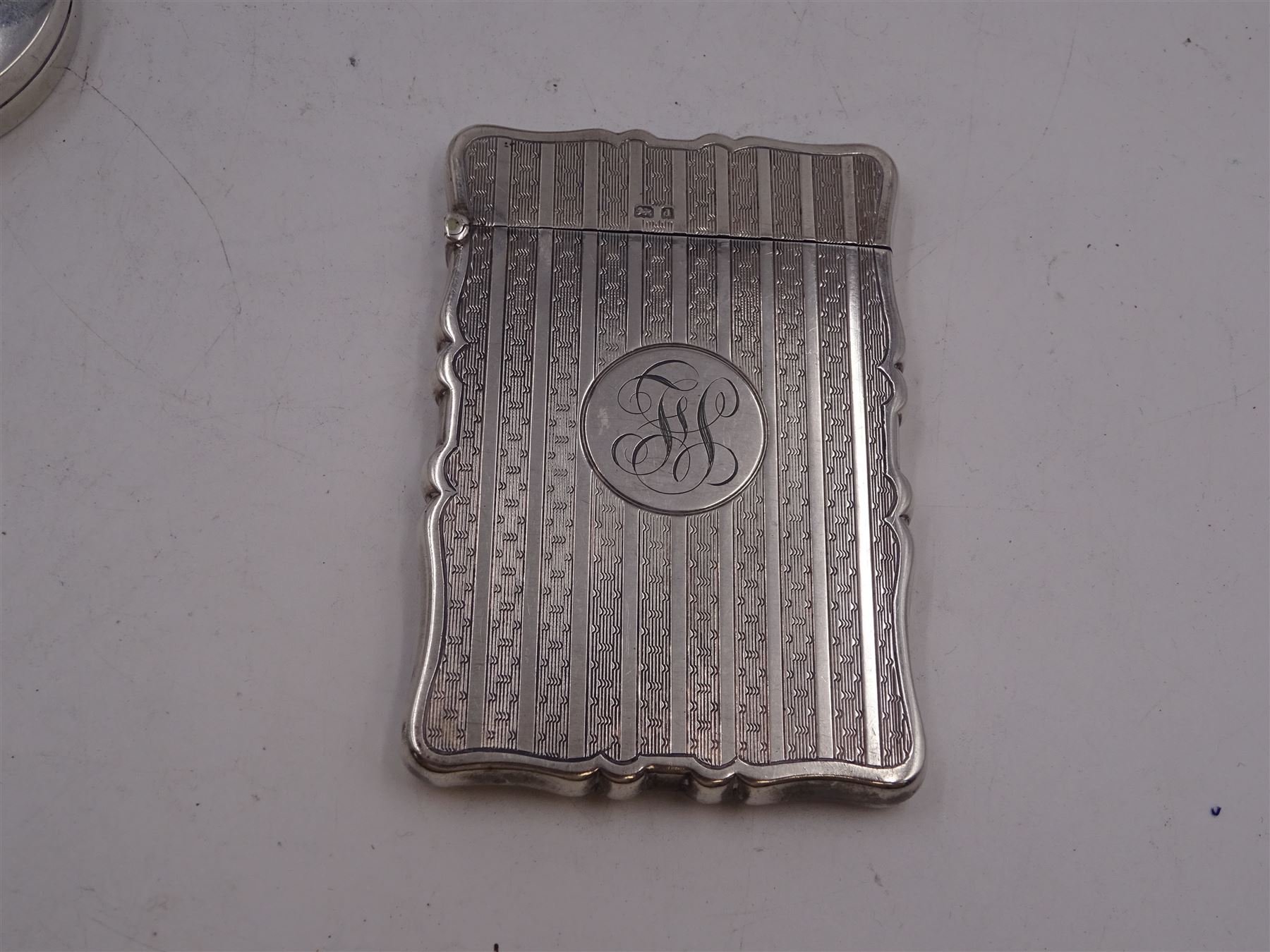 Edwardian silver card case, of rectangular form with shaped outer edge and engine turned linear decoration to body, with central monogrammed circular cartouche, H9.2cm, hallmarked Deakin & Francis Ltd, Birmingham 1903, together with a 1920s silver jewellery box, of plain oval drum form, engraved 'May' to hinged cover, opening to reveal part silk lined interior, upon four pad feet, H4.5cm, hallmarked J & R Griffin Ltd, Chester 1922 and a 1930s silver box, of circular form, engraved with monogram to hinged cover, hallmarked Barker Brothers Silver Ltd, Birmingham 1932