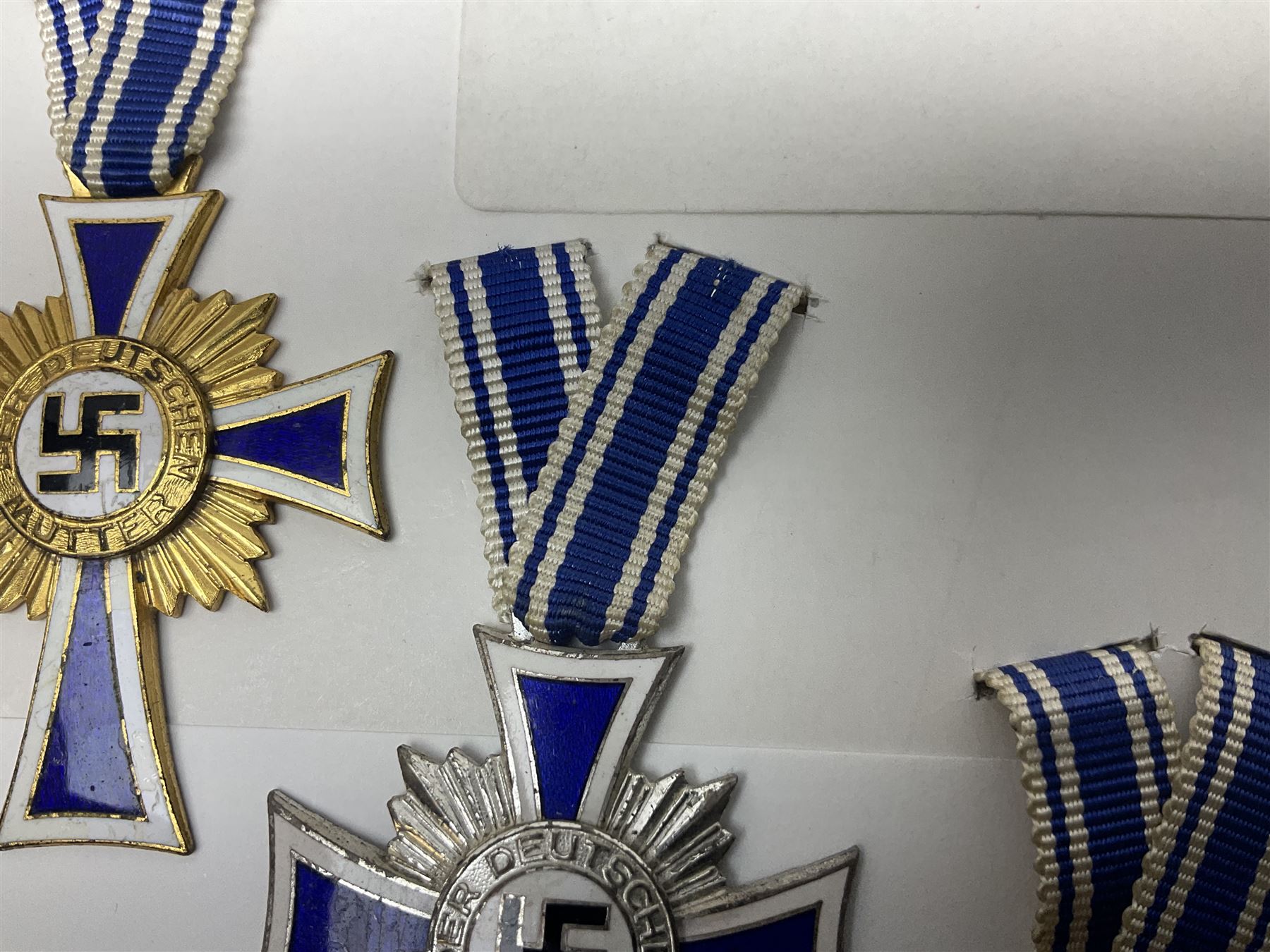 WWII set of three German Mother's Crosses, 1st Class in gilt, 2nd Class in silver and 3rd Class in bronze; all with ribbons (3)