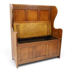 Early 20th century oak box settle, panelled back with arcaded carved rail, swept sides and arms, hinged seat with storage, panelled front