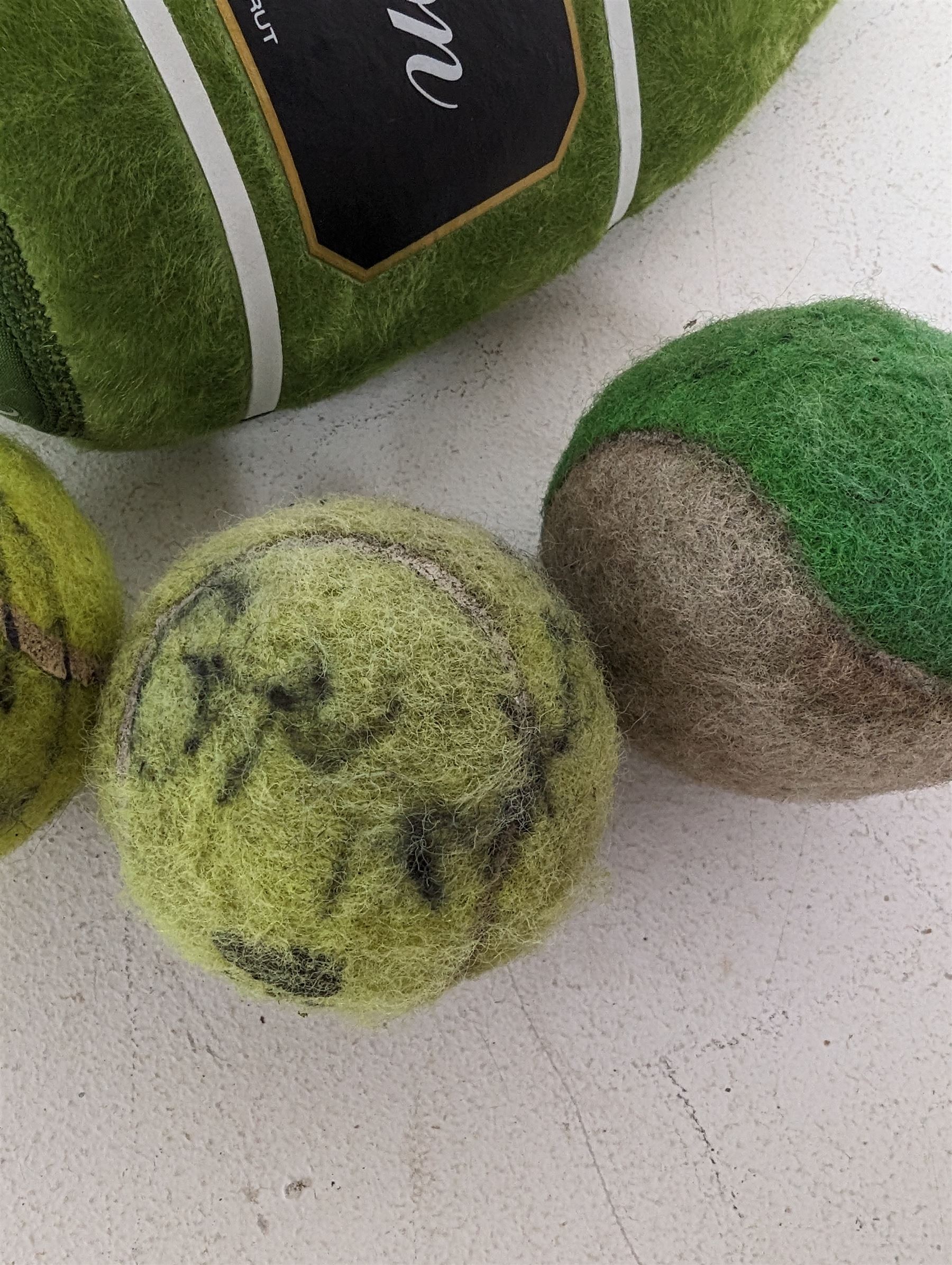 Three tennis balls, two with indistinct signatures, in Wimbledon Lansons Champagne cooler case
